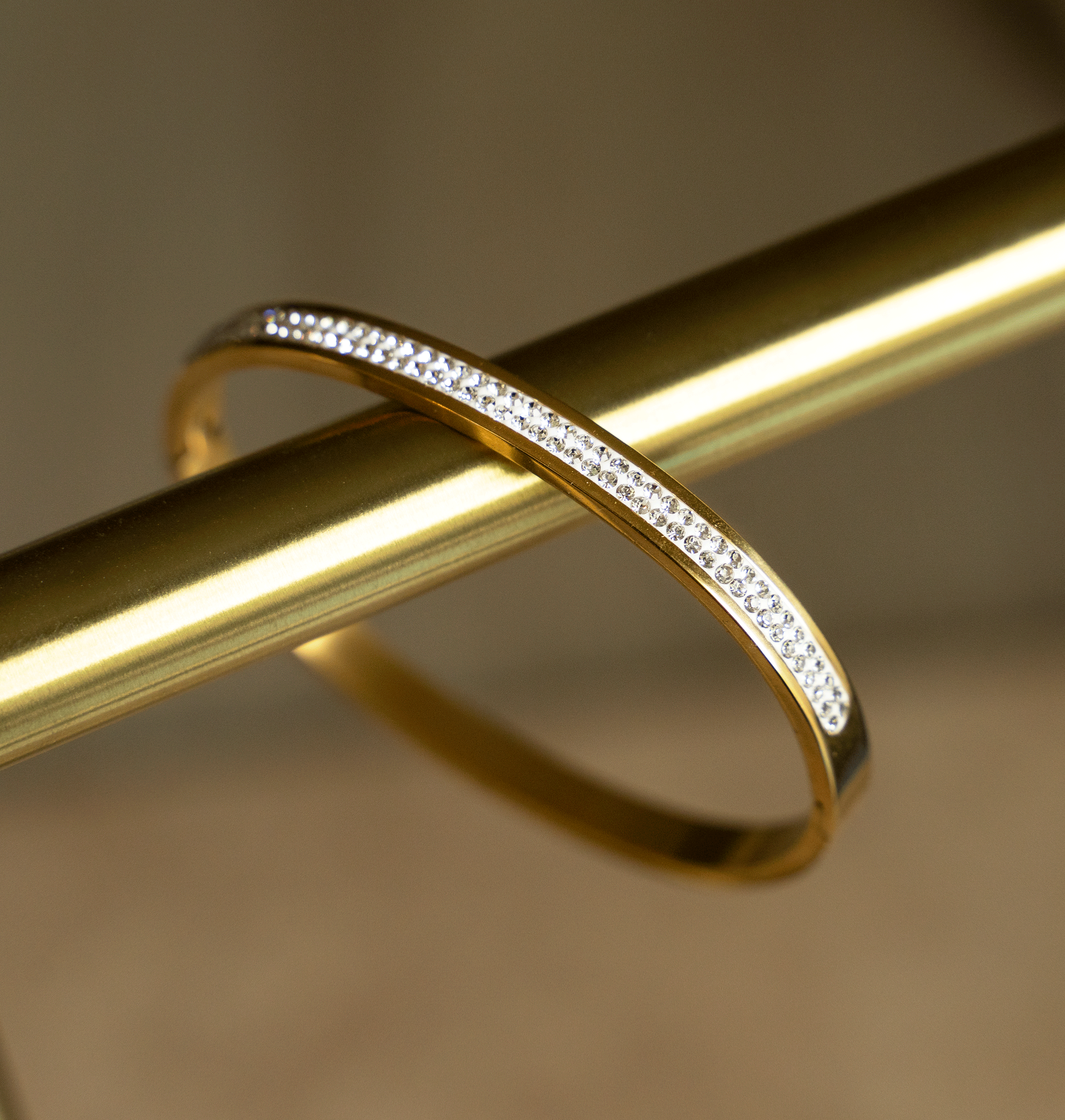 The BRIDGET Bangle featuring a double row of round brilliant cut stones in 18K gold plated stainless steel, showcasing elegance and style.