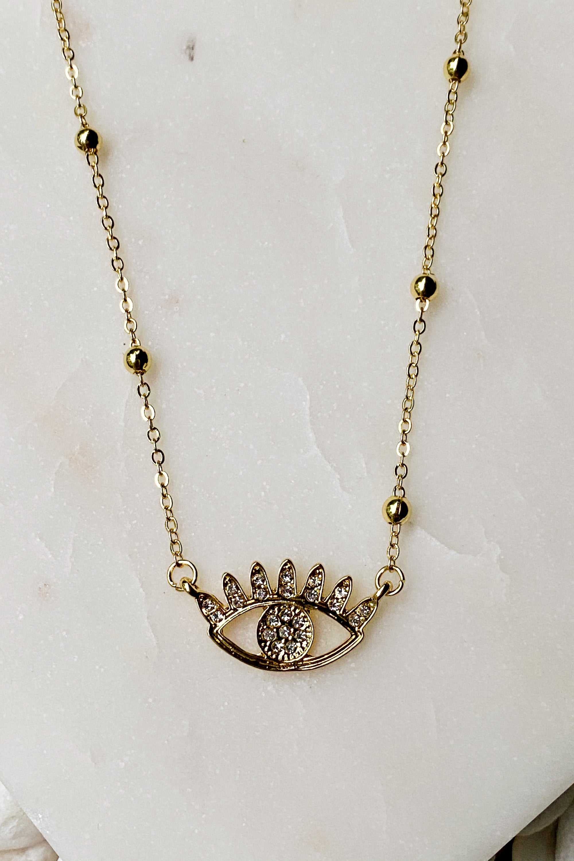 Bright & Studded Eye Necklace featuring a devil eye pendant with rhinestones and golden ball beads on a chain.