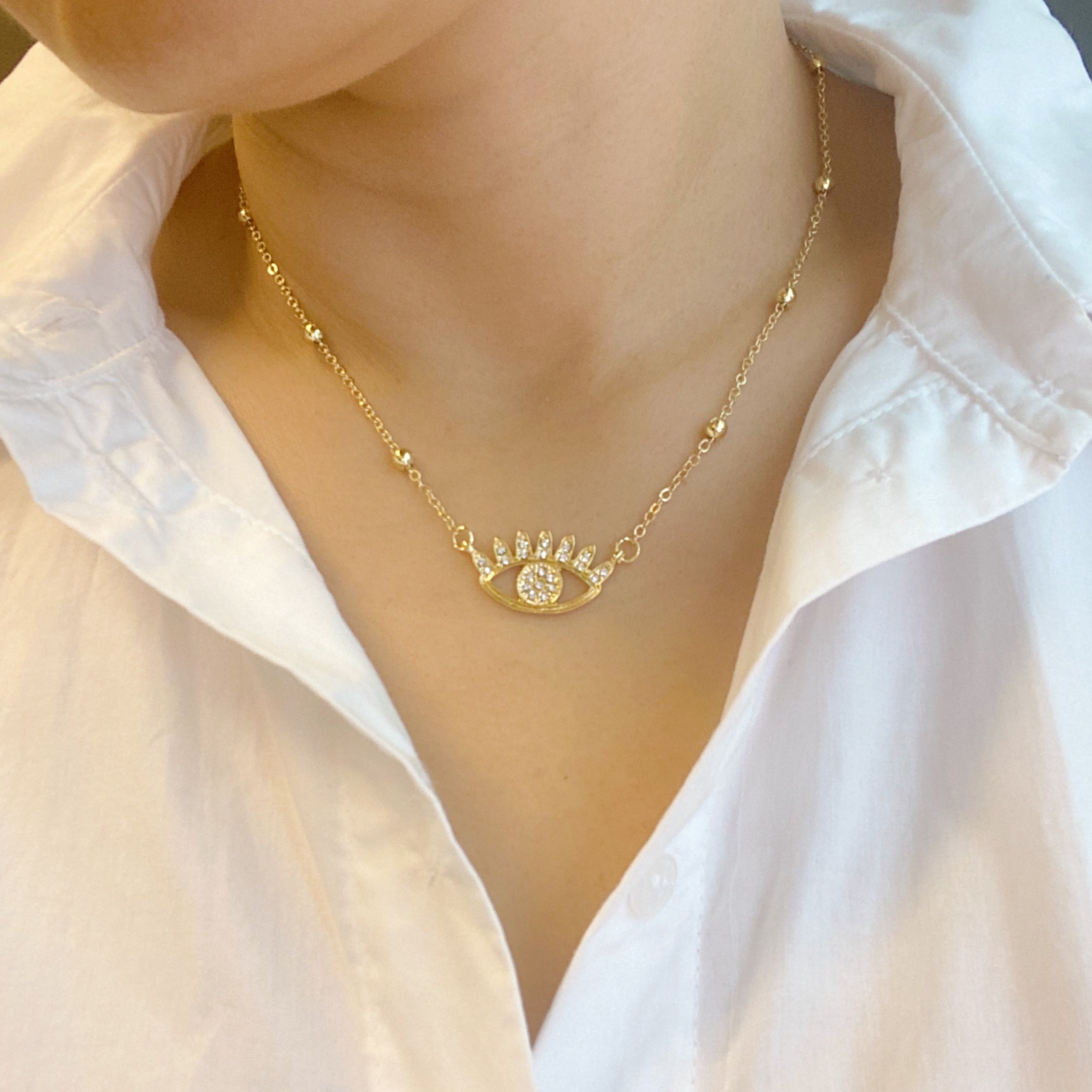 Bright & Studded Eye Necklace featuring a devil eye pendant with rhinestones and golden ball beads on a chain.