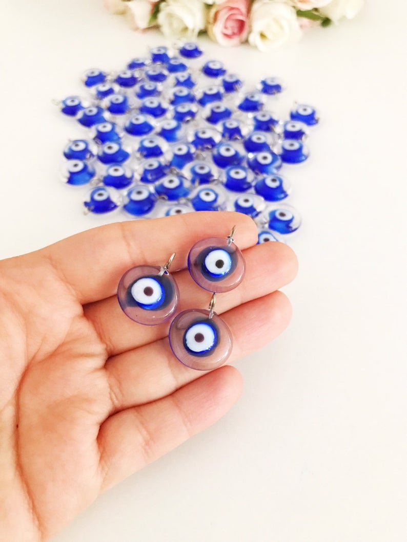 A collection of 100 blue glass evil eye charms, handmade Murano glass beads with a vibrant blue color, ideal for DIY jewelry projects.