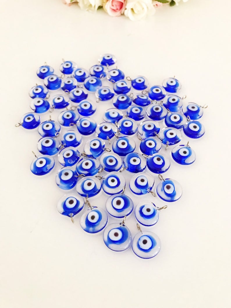 A collection of 100 blue glass evil eye charms, handmade Murano glass beads with a vibrant blue color, ideal for DIY jewelry projects.
