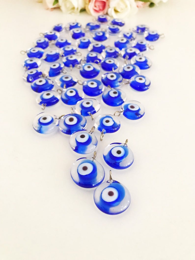 A collection of 100 blue glass evil eye charms, handmade Murano glass beads with a vibrant blue color, ideal for DIY jewelry projects.