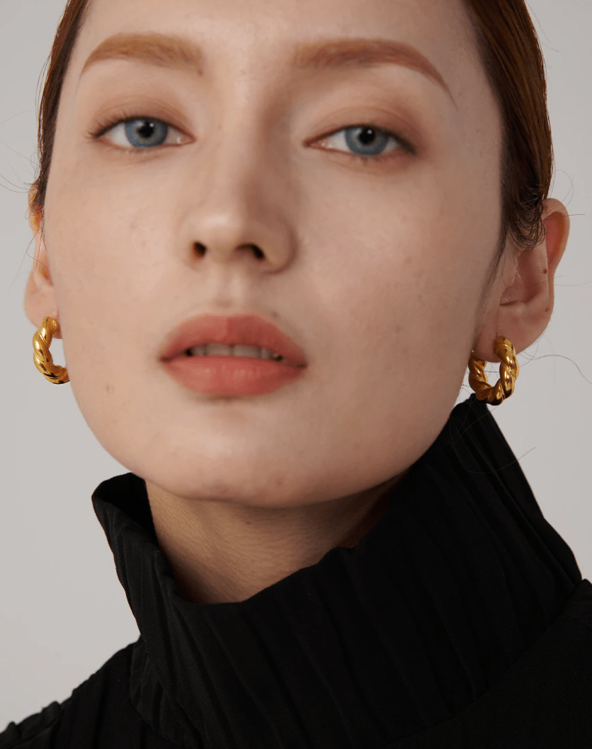 Candy Twisted Nugget Creoles earrings featuring a unique twisted design in stainless steel with 18Kt yellow gold coating.