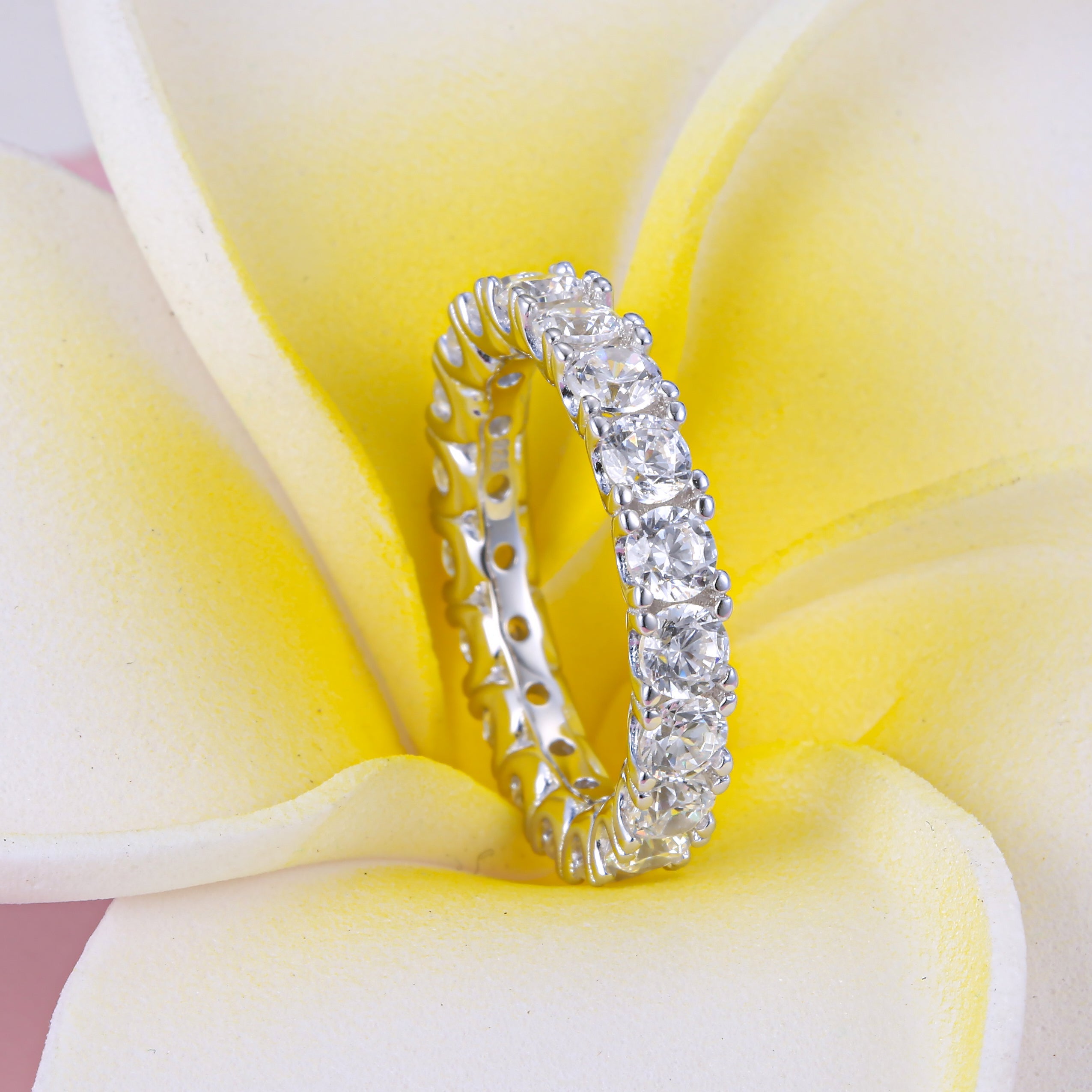 Classic Eternity Round Cut Women's Wedding Band made of sterling silver with white gold surface and white sapphires, showcasing elegance and durability.