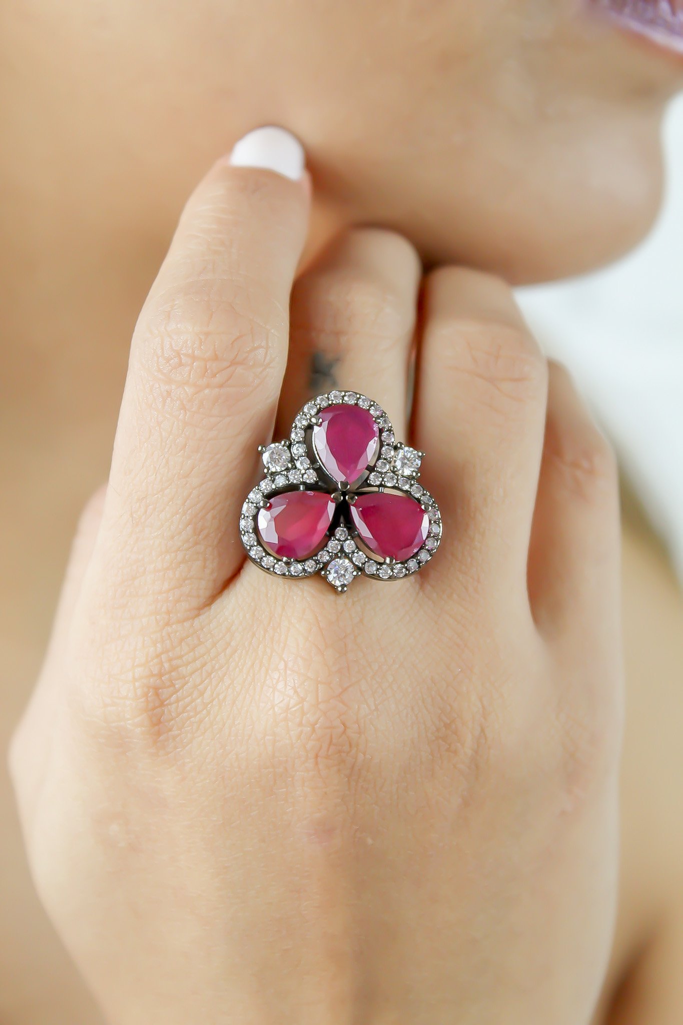 Cloverfield Ring featuring colorful sparkling zircons and adjustable design, elegantly displayed on a soft surface.