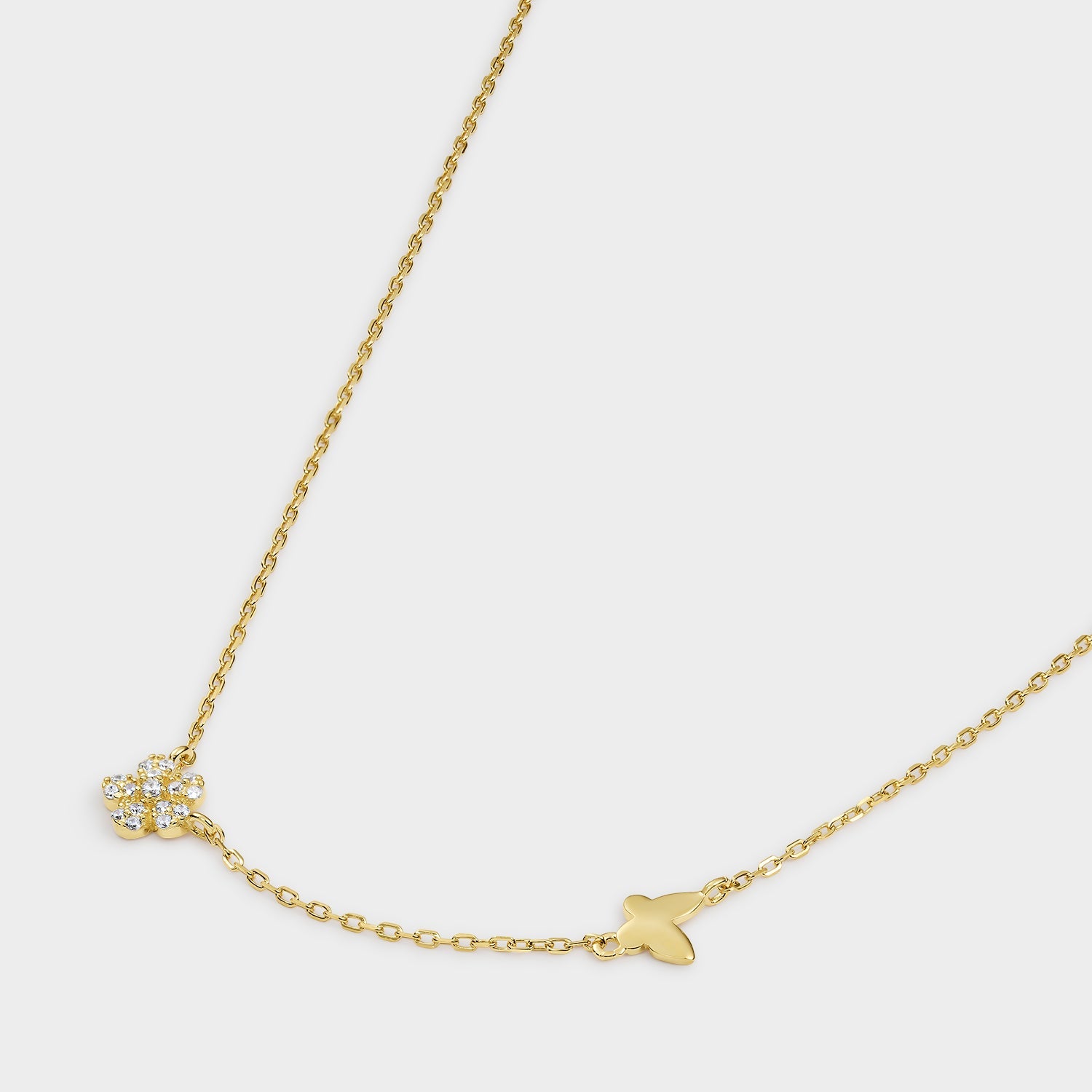 Collar de plata bañada en oro amarillo con diseño de mariposa y flor, adornado con circonitas blancas brillantes.