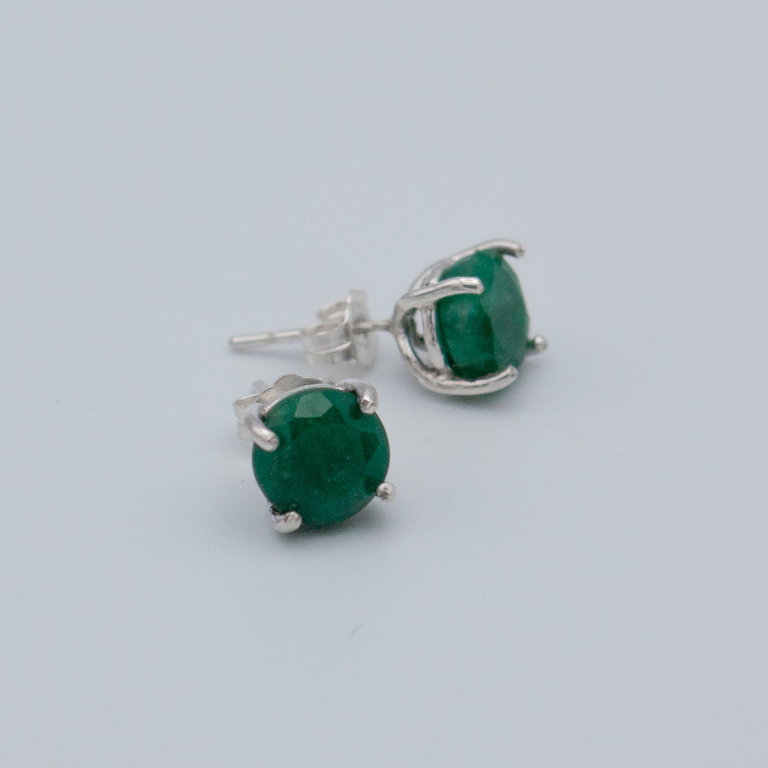 Elegant Colombian emerald stud earrings set in 925 sterling silver, featuring a secure post back style.