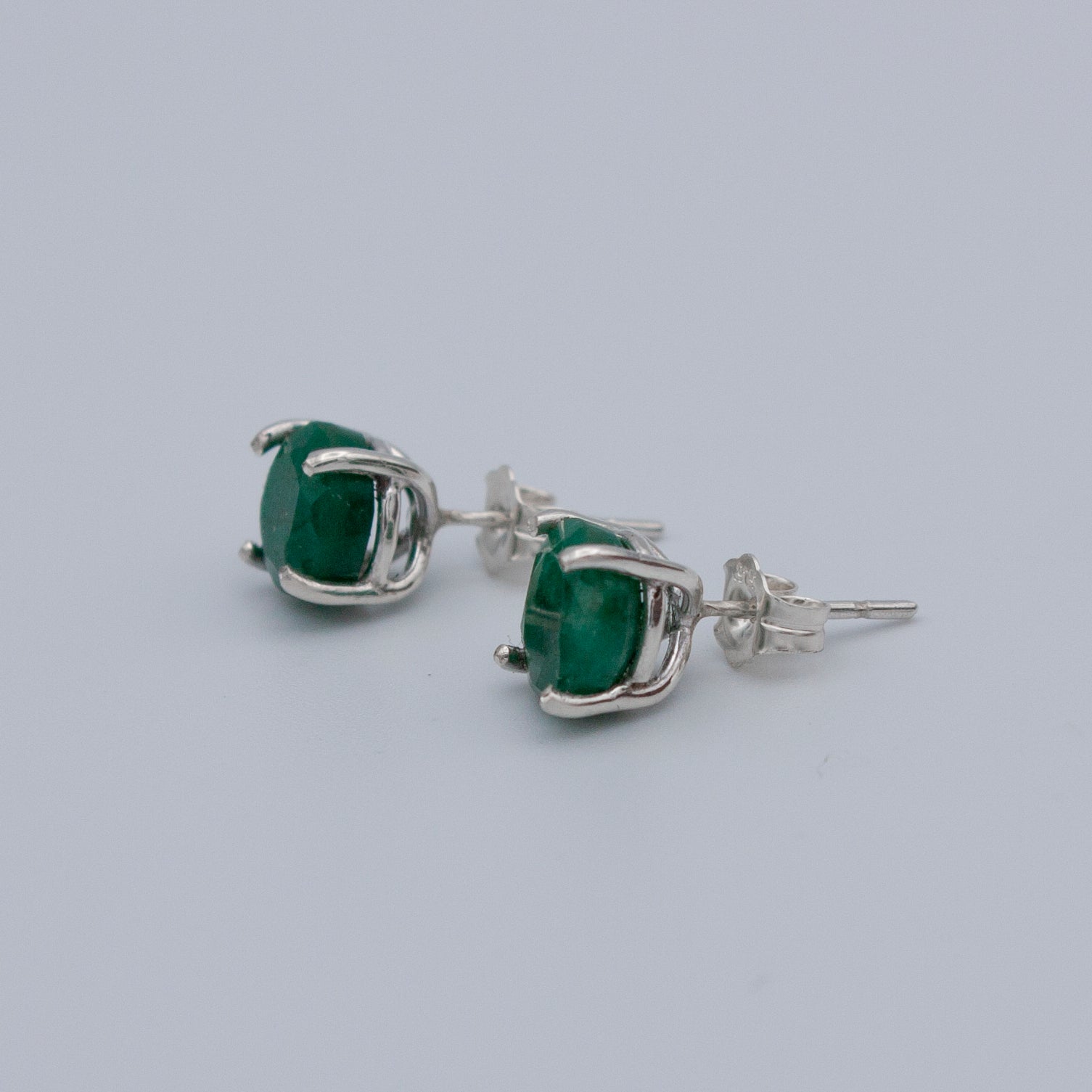 Elegant Colombian emerald stud earrings set in 925 sterling silver, featuring a secure post back style.