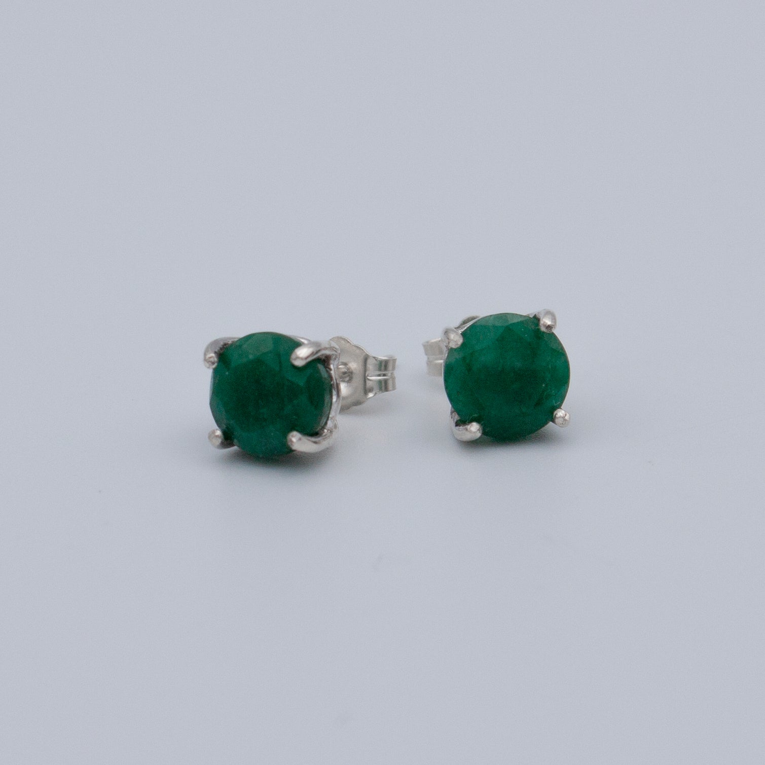Elegant Colombian emerald stud earrings set in 925 sterling silver, featuring a secure post back style.