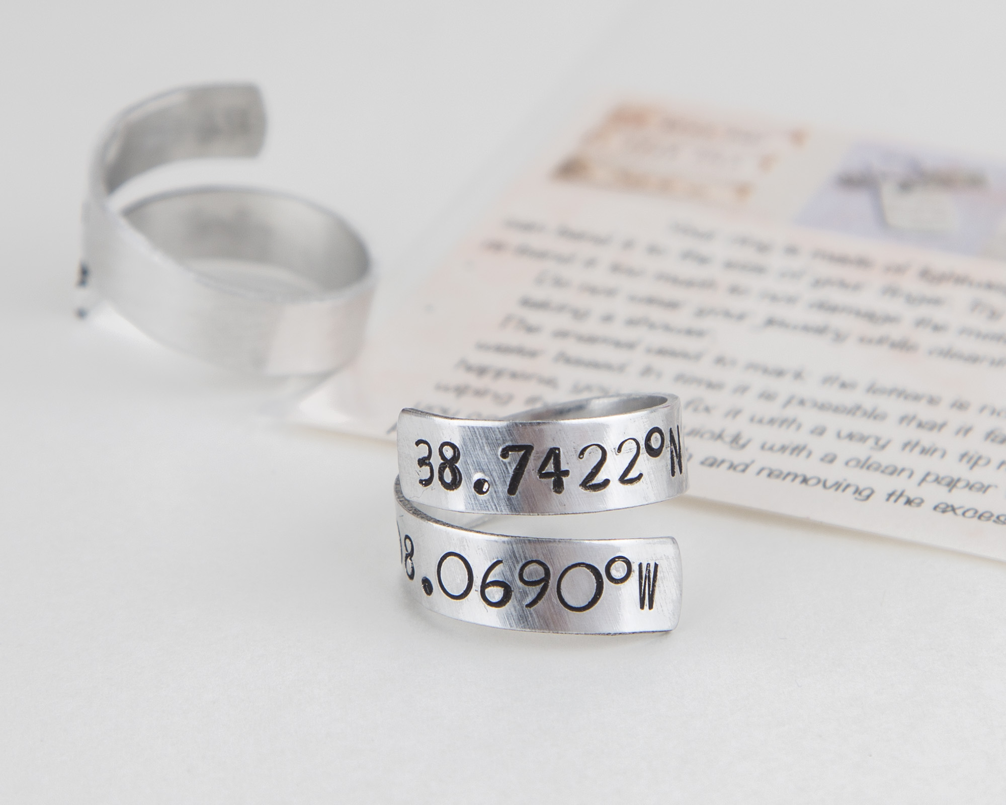 Adjustable aluminum coordinates ring, hand-stamped with personalized location details, perfect for long-distance relationships.