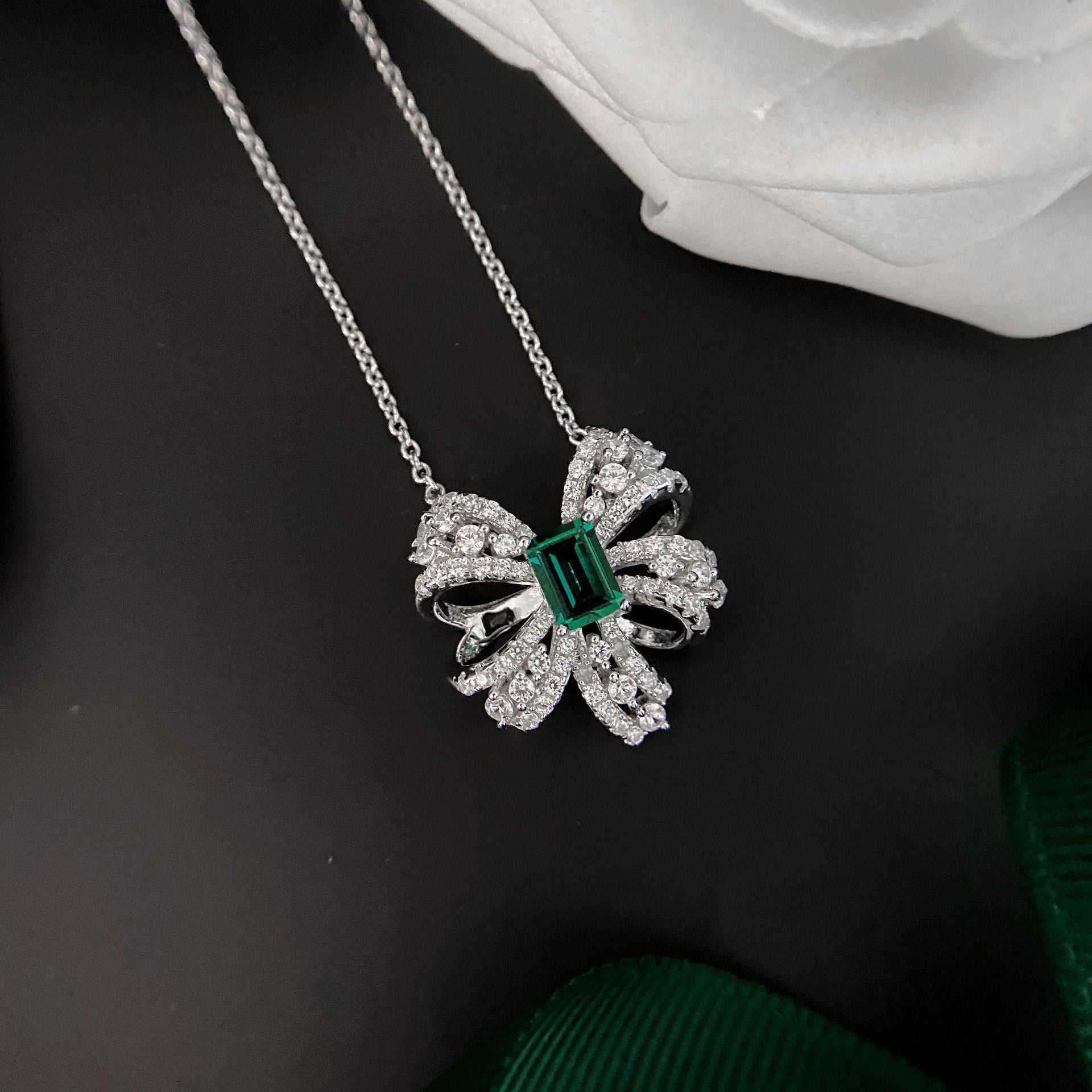 Delicate necklace featuring a created emerald set in 925 sterling silver with white gold finish, adjustable chain.