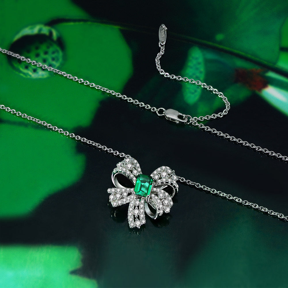 Delicate necklace featuring a created emerald set in 925 sterling silver with white gold finish, adjustable chain.