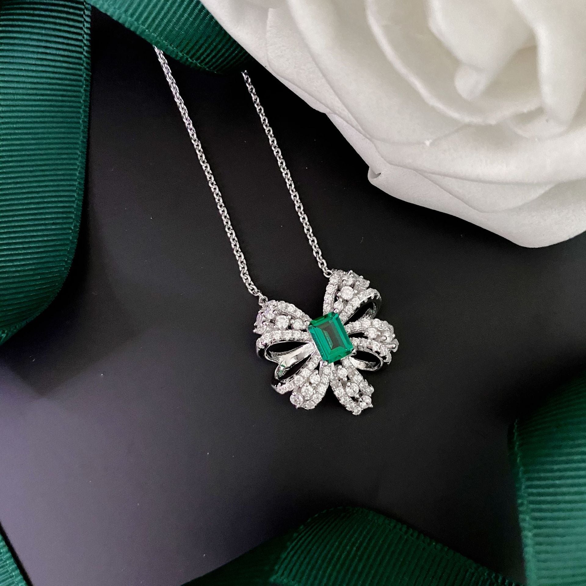 Delicate necklace featuring a created emerald set in 925 sterling silver with white gold finish, adjustable chain.