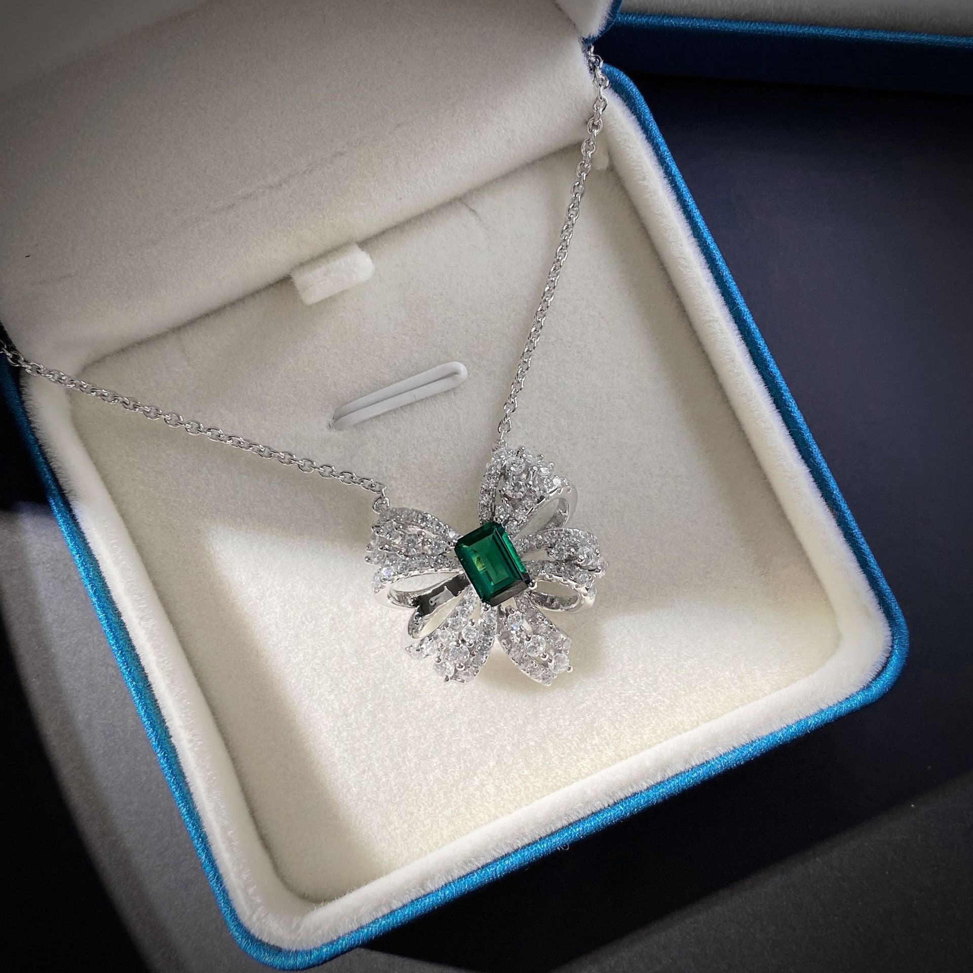 Delicate necklace featuring a created emerald set in 925 sterling silver with white gold finish, adjustable chain.