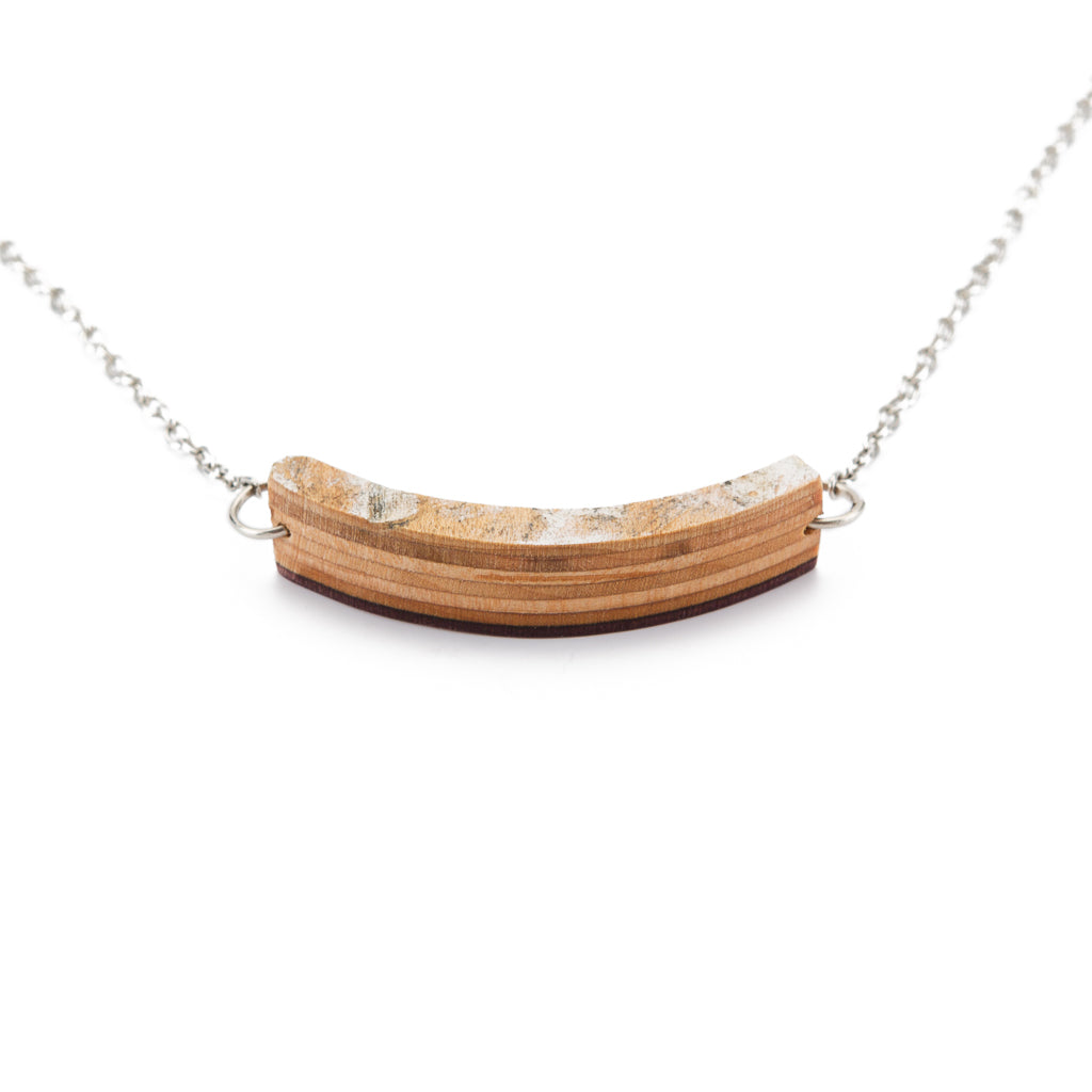 Crescent-shaped necklace made from recycled skateboard wood, showcasing vibrant colors and unique patterns.