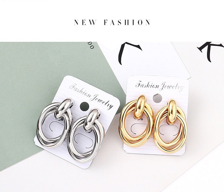 A pair of stylish crossed oval hoop earrings made from alloy and steel, showcasing a modern design.