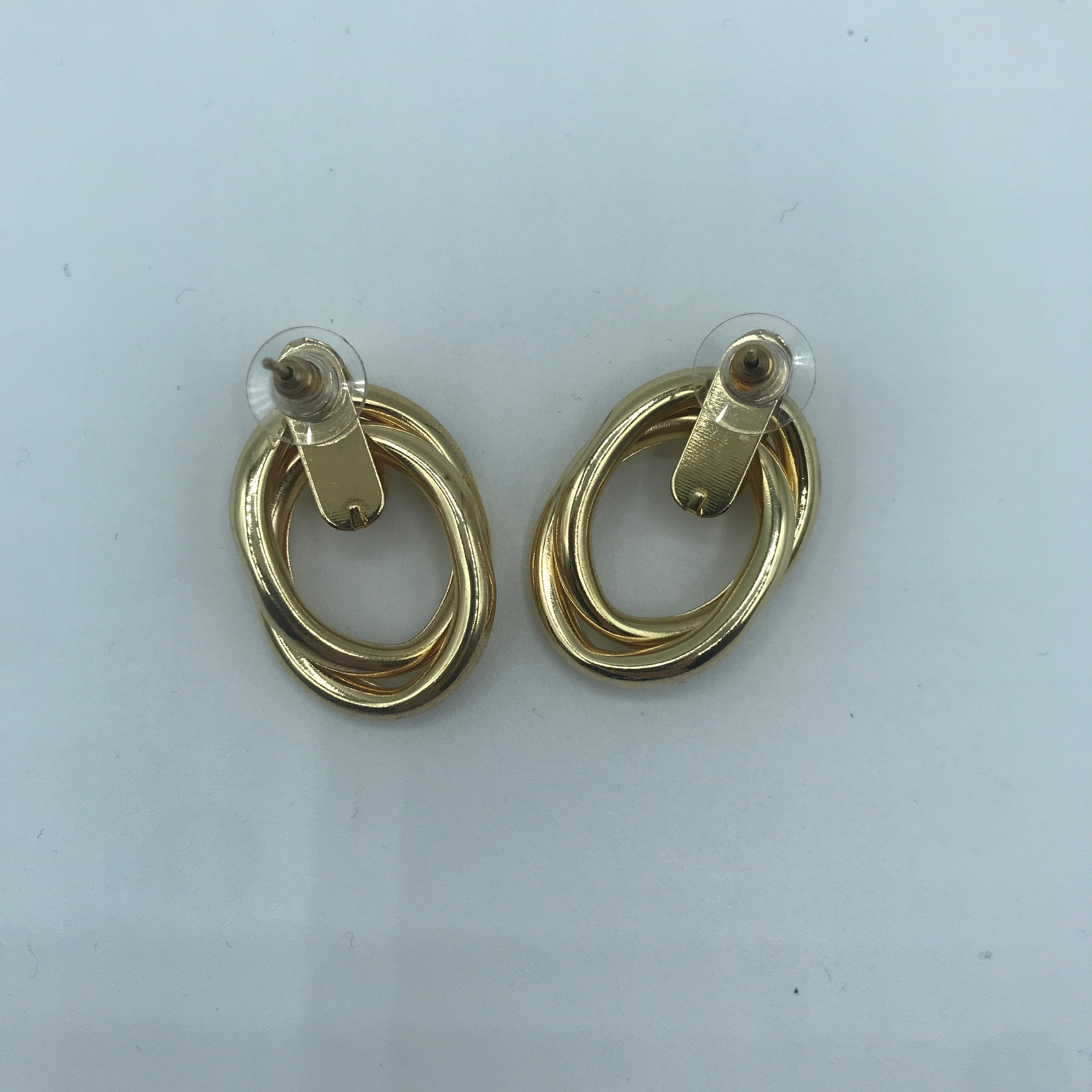 A pair of stylish crossed oval hoop earrings made from alloy and steel, showcasing a modern design.