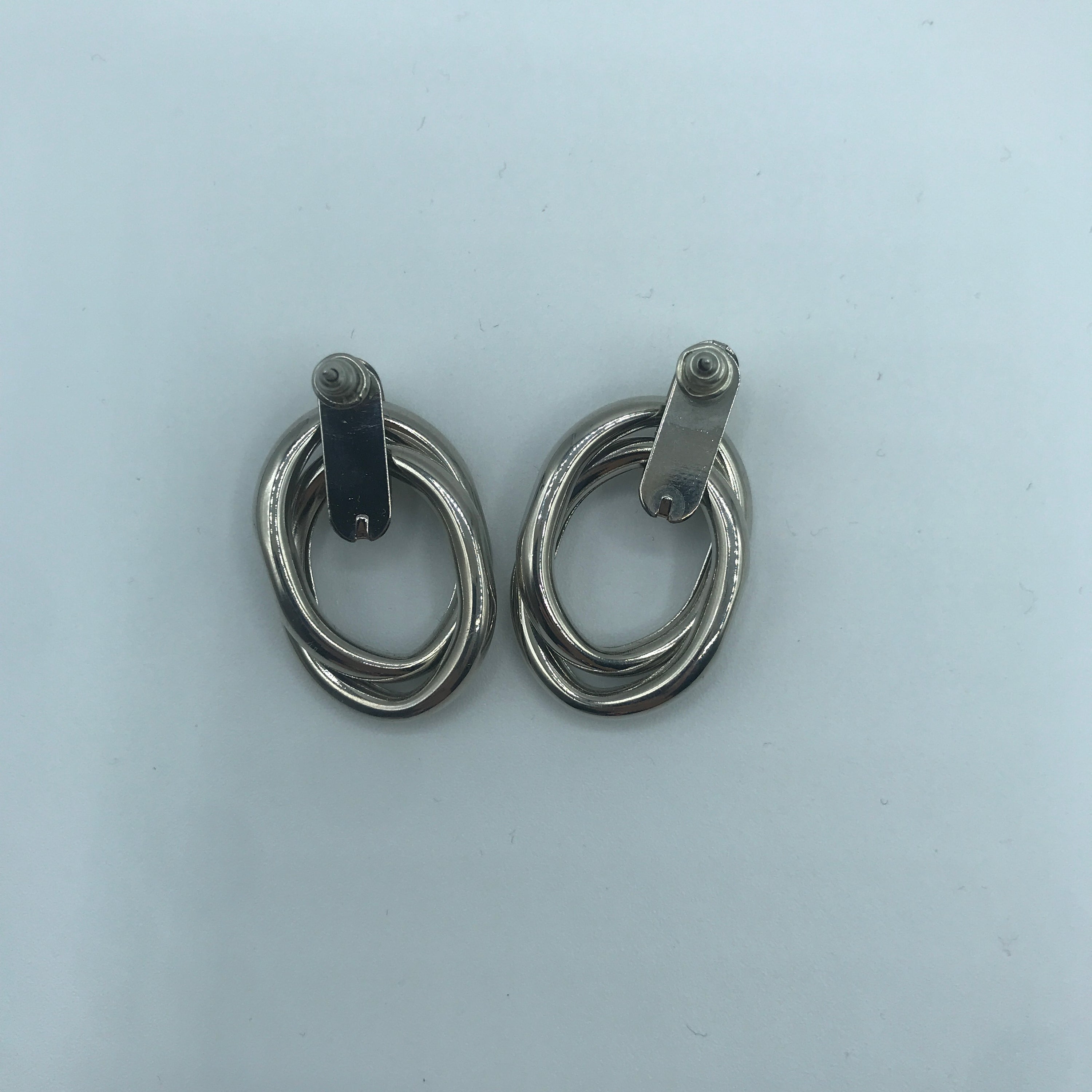 A pair of stylish crossed oval hoop earrings made from alloy and steel, showcasing a modern design.