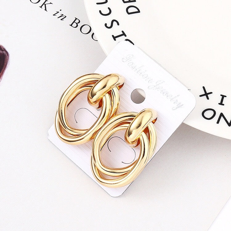 A pair of stylish crossed oval hoop earrings made from alloy and steel, showcasing a modern design.