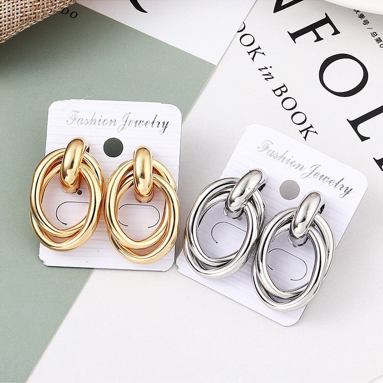 A pair of stylish crossed oval hoop earrings made from alloy and steel, showcasing a modern design.