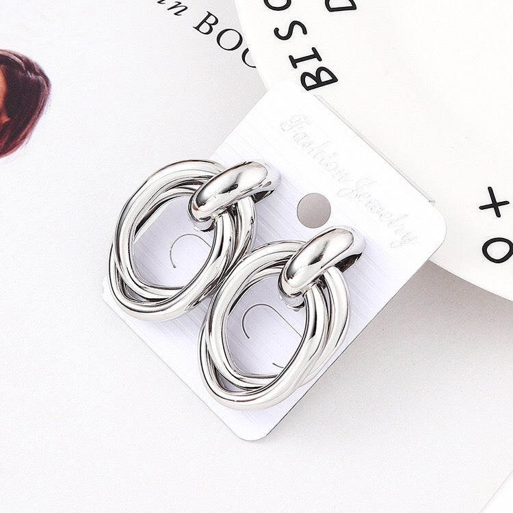 A pair of stylish crossed oval hoop earrings made from alloy and steel, showcasing a modern design.