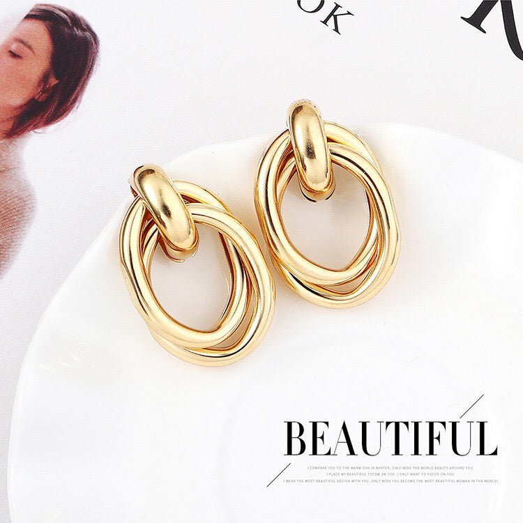 A pair of stylish crossed oval hoop earrings made from alloy and steel, showcasing a modern design.