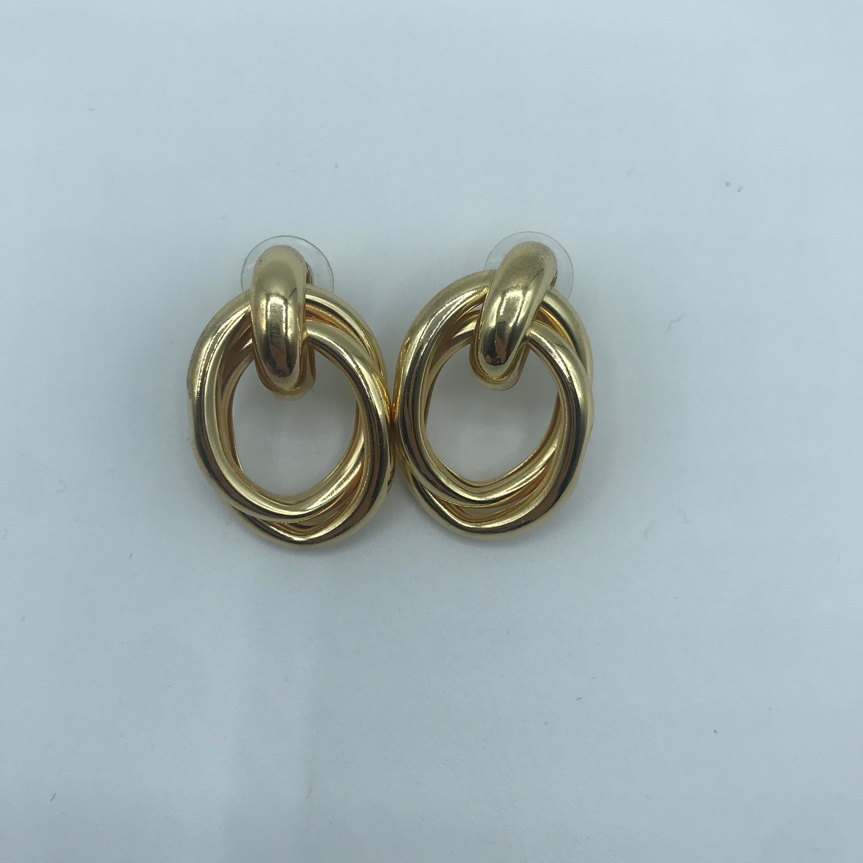 A pair of stylish crossed oval hoop earrings made from alloy and steel, showcasing a modern design.