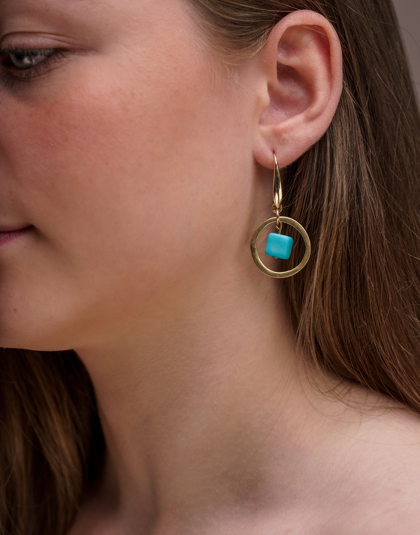 A pair of stylish Cubo Brass Hoop Earrings, featuring a sleek design and brass hooks, displayed in an eco-friendly bag.