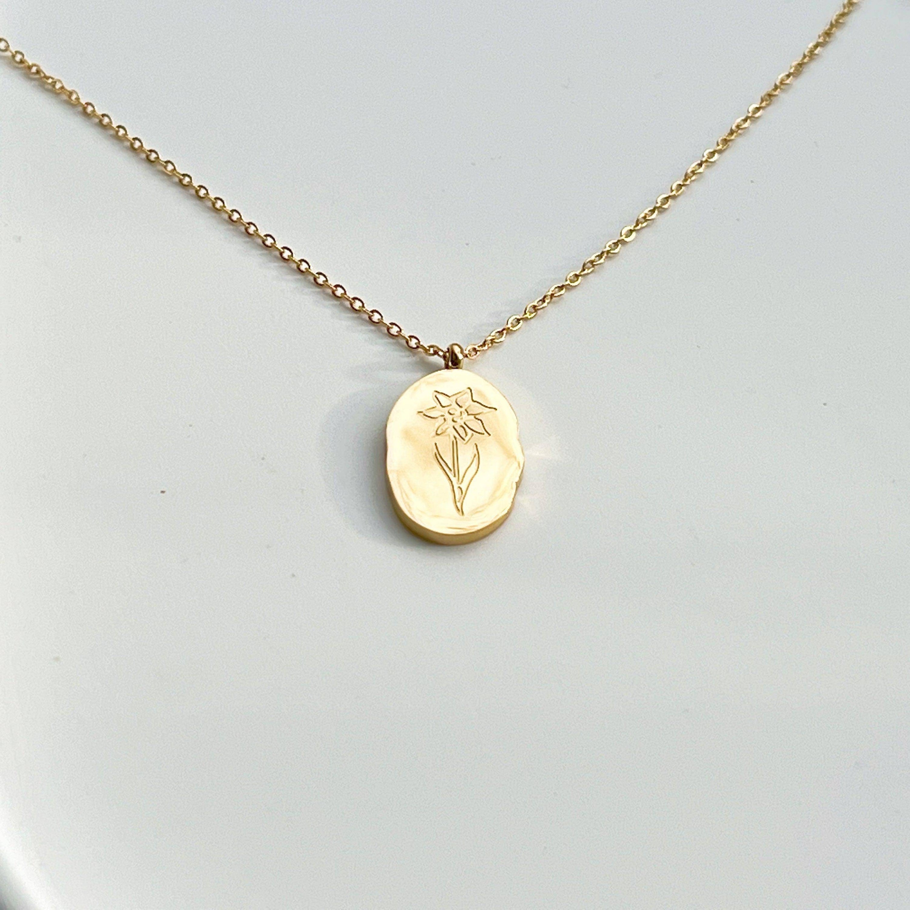 Daffodil Pendant Necklace featuring a gold plated stainless steel charm with a daffodil flower pattern, displayed elegantly on a soft background.