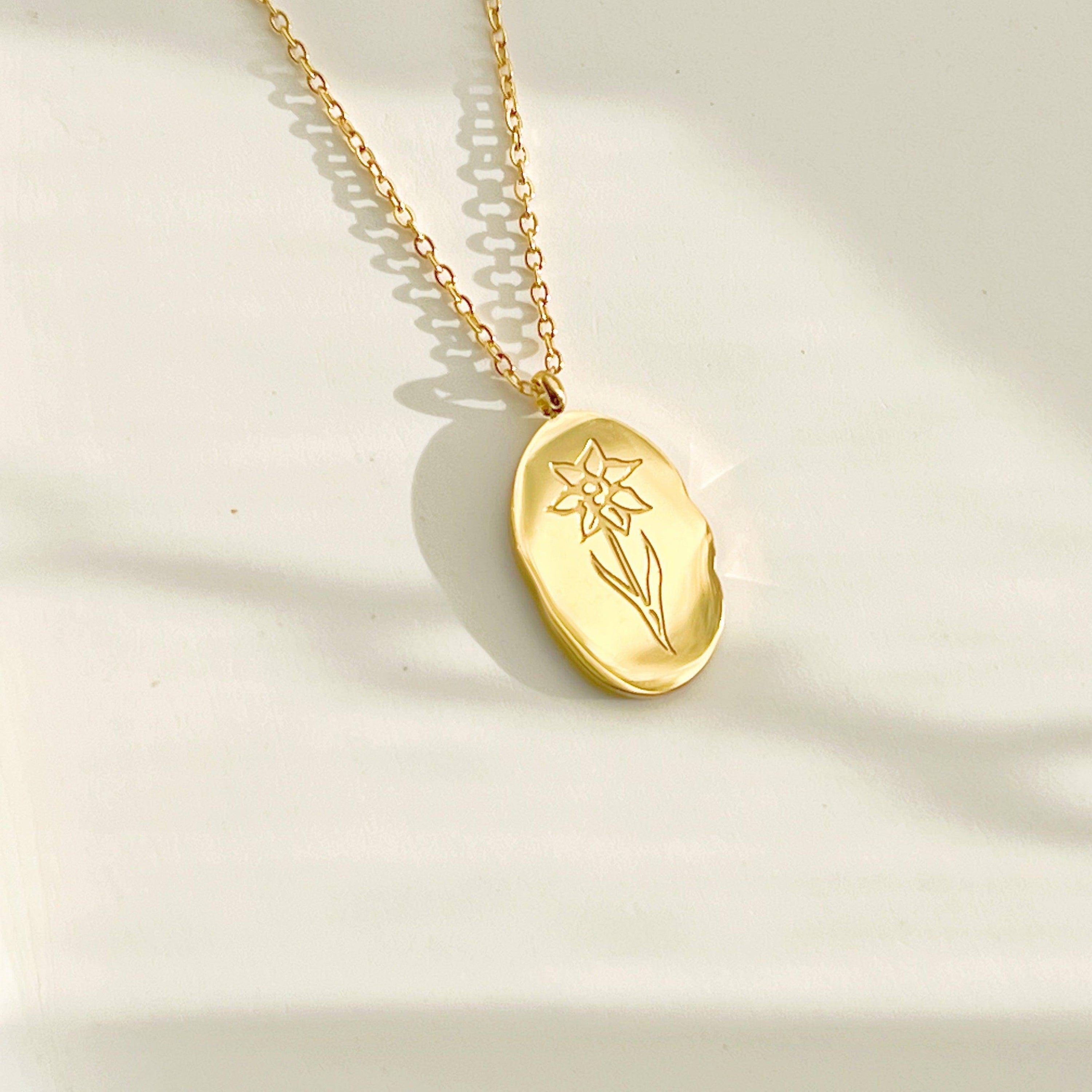 Daffodil Pendant Necklace featuring a gold plated stainless steel charm with a daffodil flower pattern, displayed elegantly on a soft background.