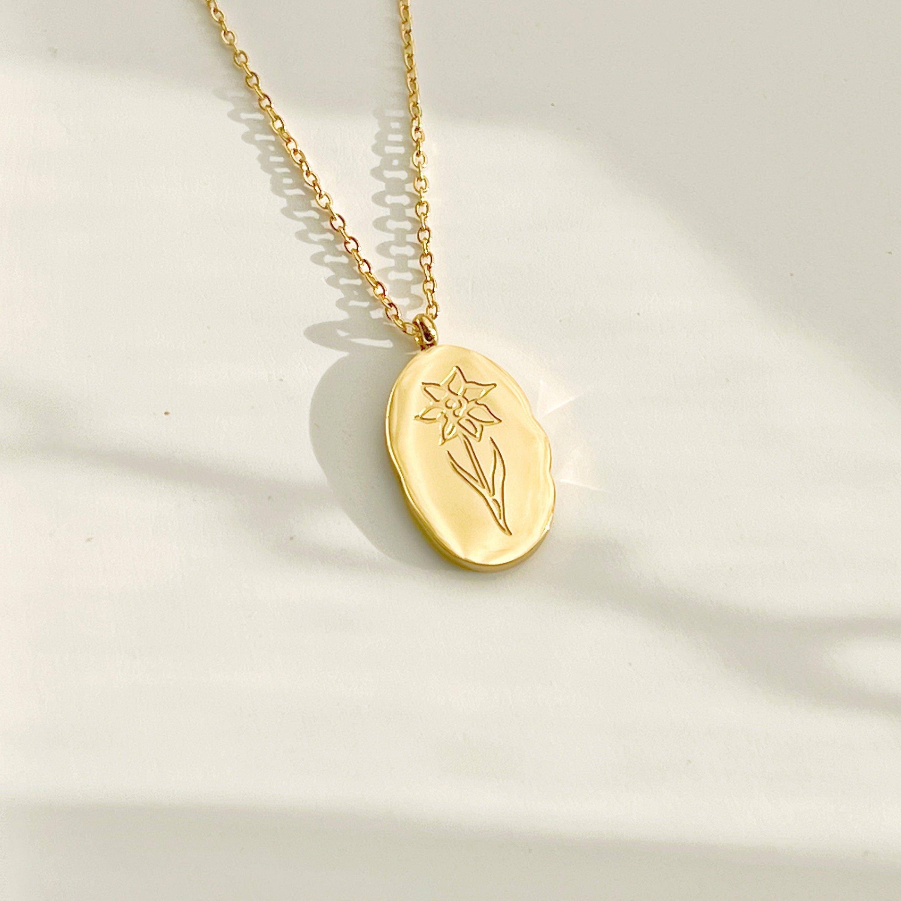 Daffodil Pendant Necklace featuring a gold plated stainless steel charm with a daffodil flower pattern, displayed elegantly on a soft background.