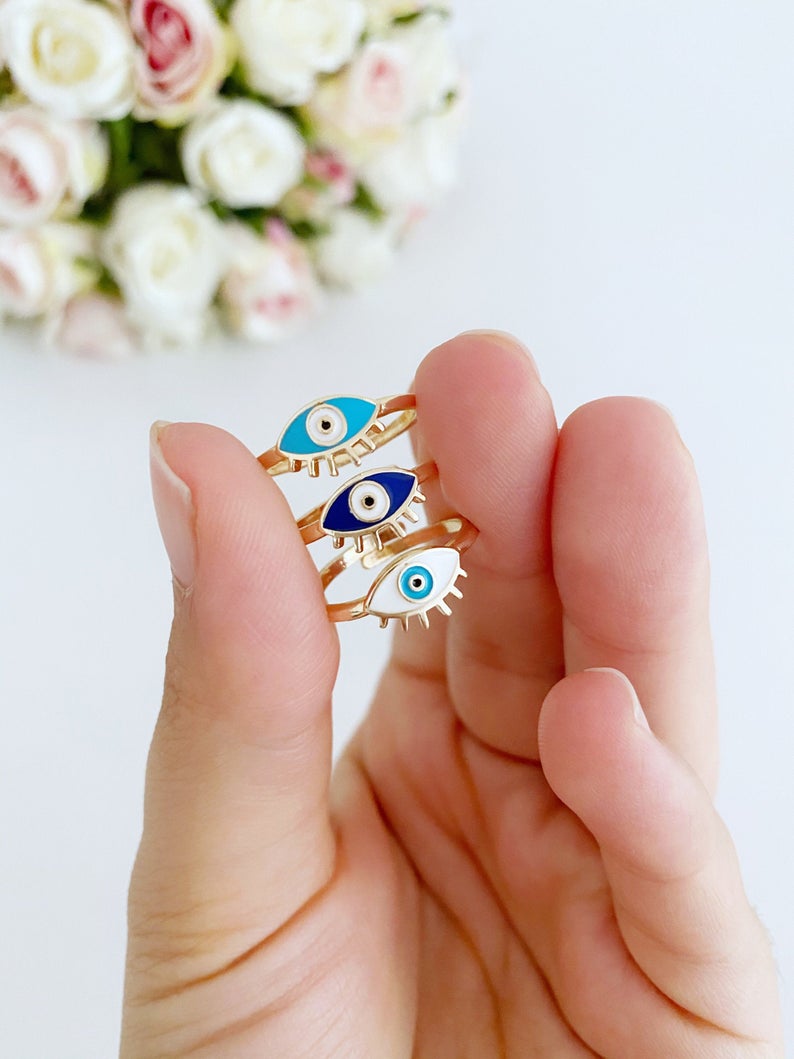 Dainty Adjustable Evil Eye Ring featuring a thin gold band and an oval evil eye in blue, turquoise, and white colors.