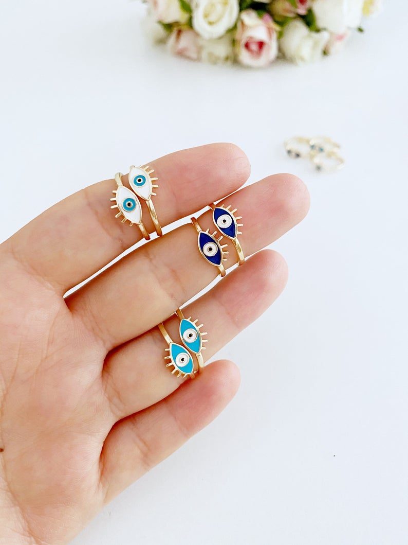 Dainty Adjustable Evil Eye Ring featuring a thin gold band and an oval evil eye in blue, turquoise, and white colors.