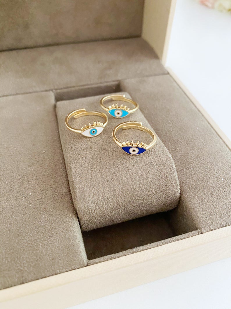 Dainty Adjustable Evil Eye Ring featuring a thin gold band and an oval evil eye in blue, turquoise, and white colors.