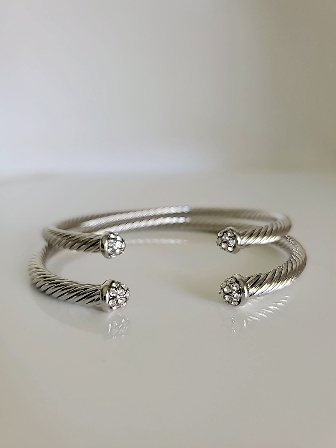 Dainty Crystals Dome Bangle in Gold and Silver with a sleek cable design and dome ends, showcasing its elegant and modern style.