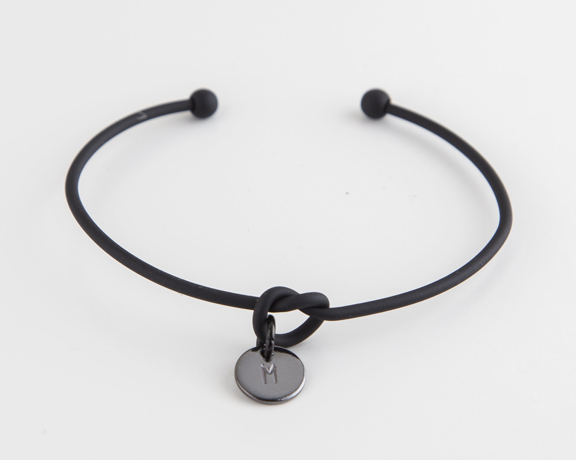 Dainty Knot Bracelet featuring a black metal wire knot design with a hand-stamped tag, adjustable size for comfort.