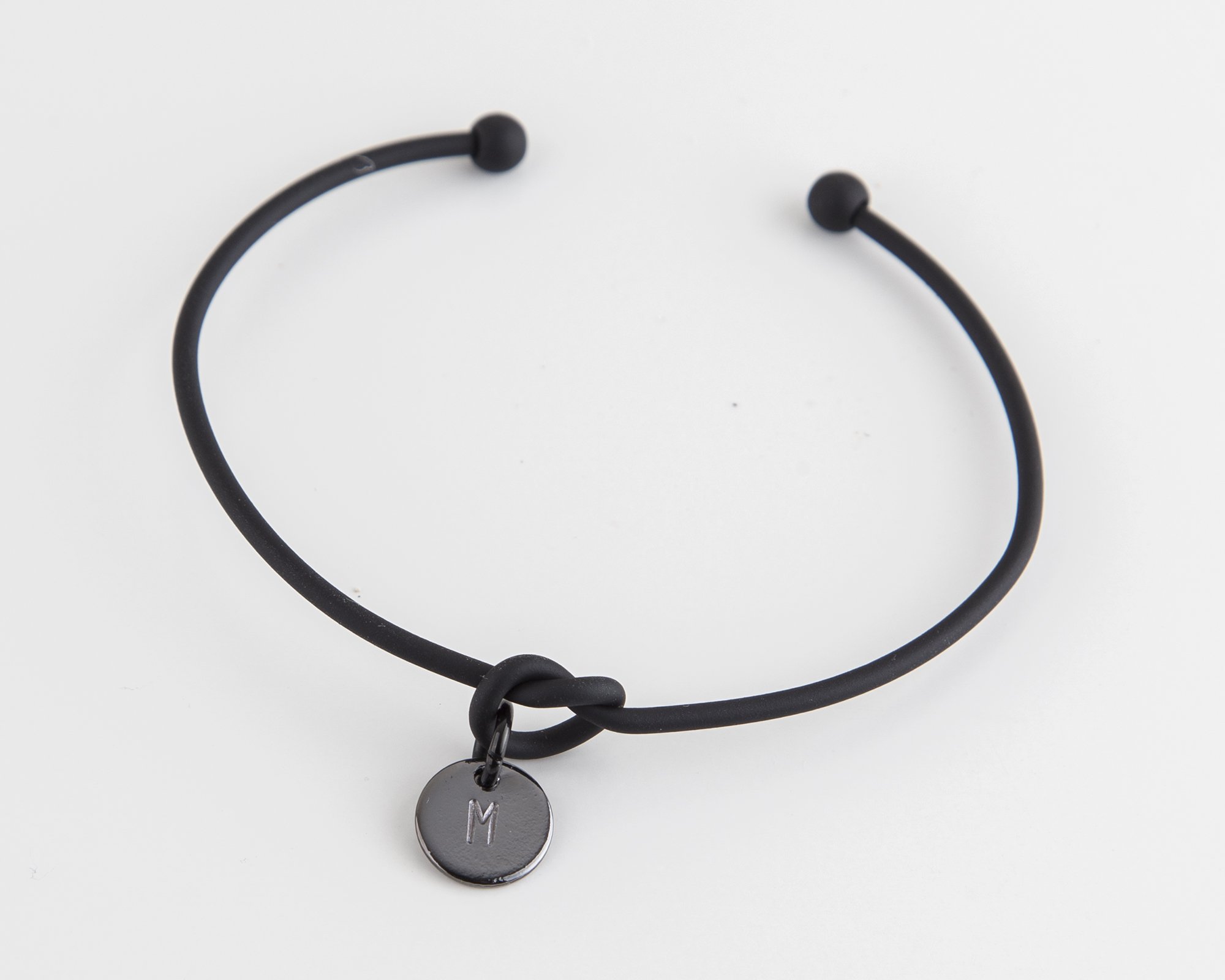 Dainty Knot Bracelet featuring a black metal wire knot design with a hand-stamped tag, adjustable size for comfort.