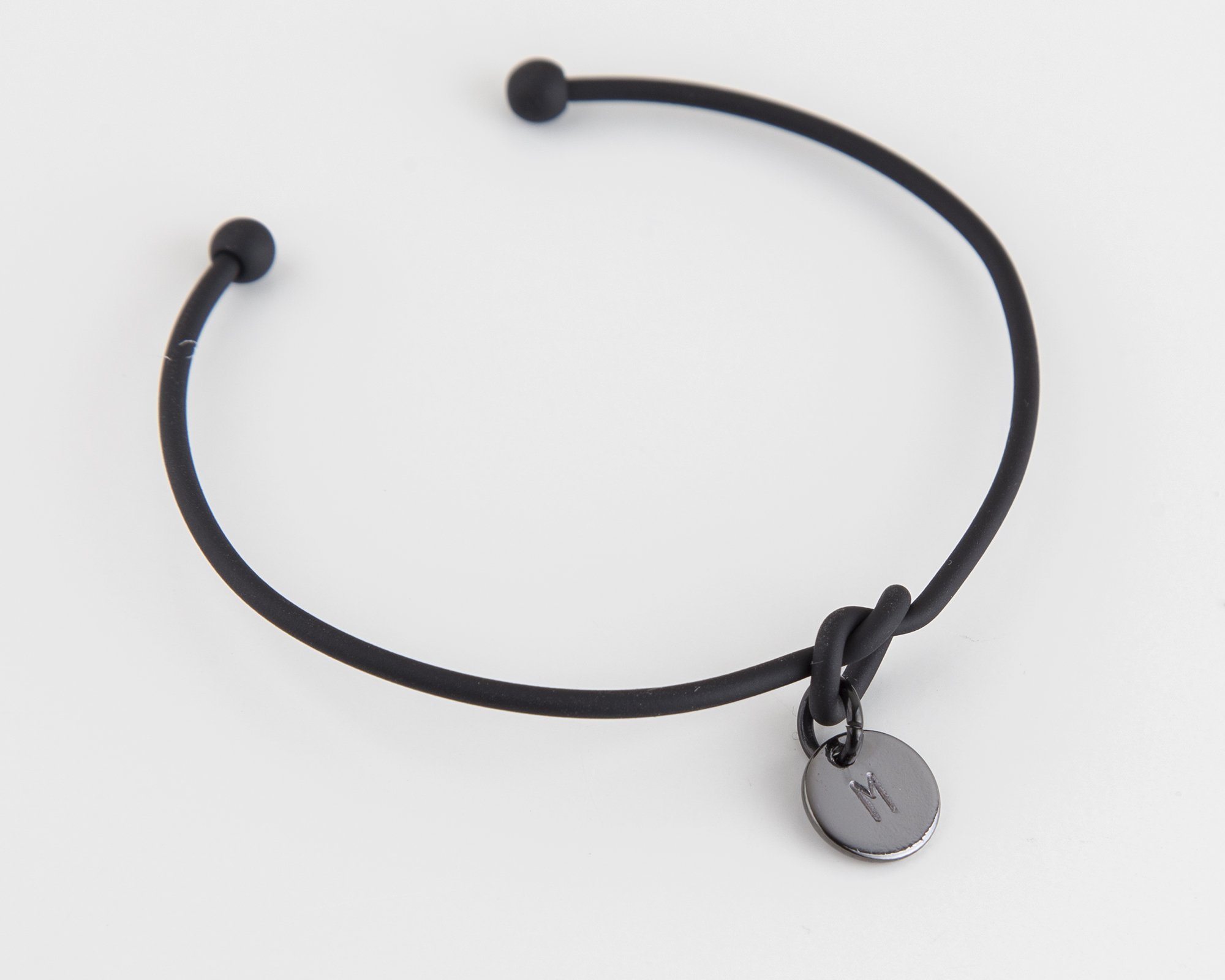 Dainty Knot Bracelet featuring a black metal wire knot design with a hand-stamped tag, adjustable size for comfort.