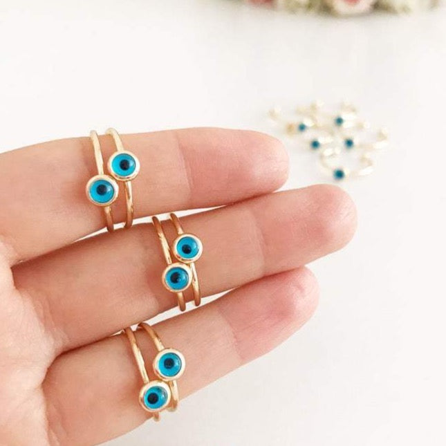 Dainty gold evil eye ring featuring a round blue bead on a thin adjustable band, perfect for everyday wear.