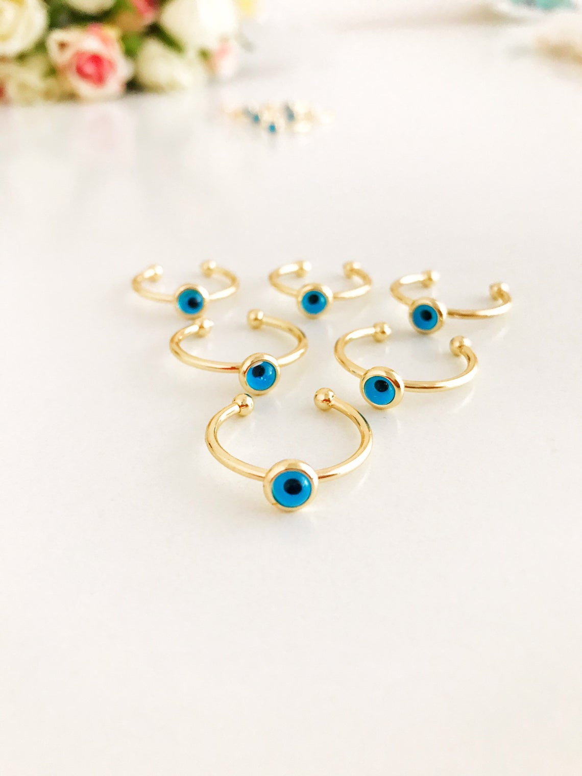 Dainty gold evil eye ring featuring a round blue bead on a thin adjustable band, perfect for everyday wear.