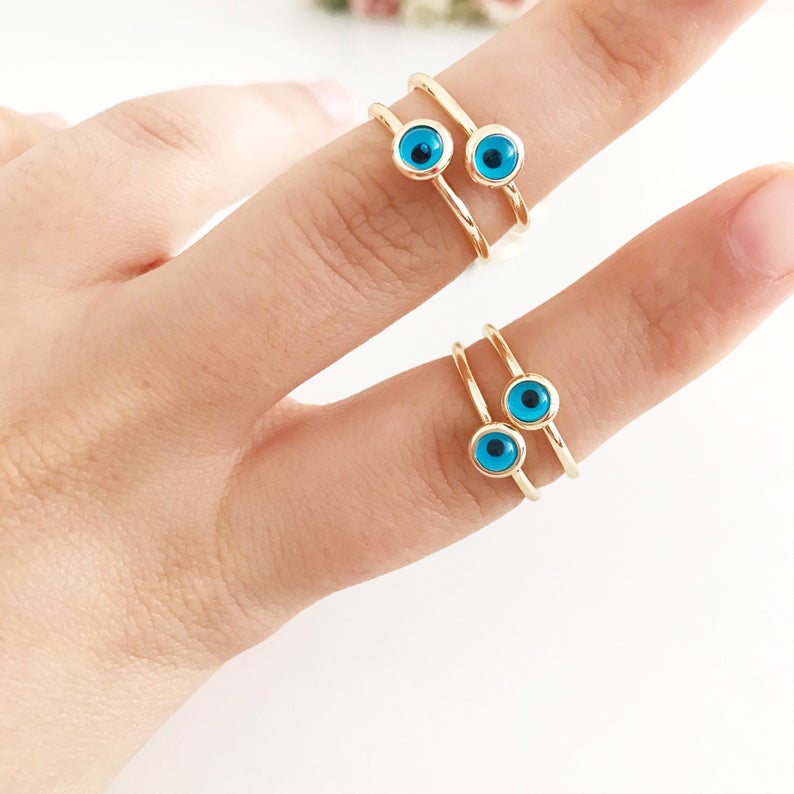 Dainty gold evil eye ring featuring a round blue bead on a thin adjustable band, perfect for everyday wear.