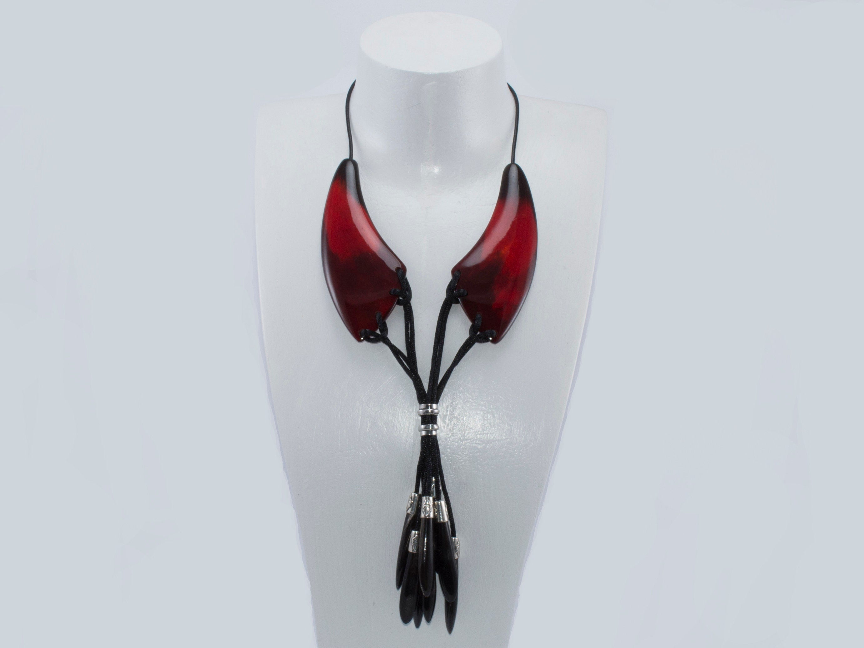 A beautiful dark red necklace made from natural horn with silver caps and teardrop-shaped endings, showcasing its unique craftsmanship.