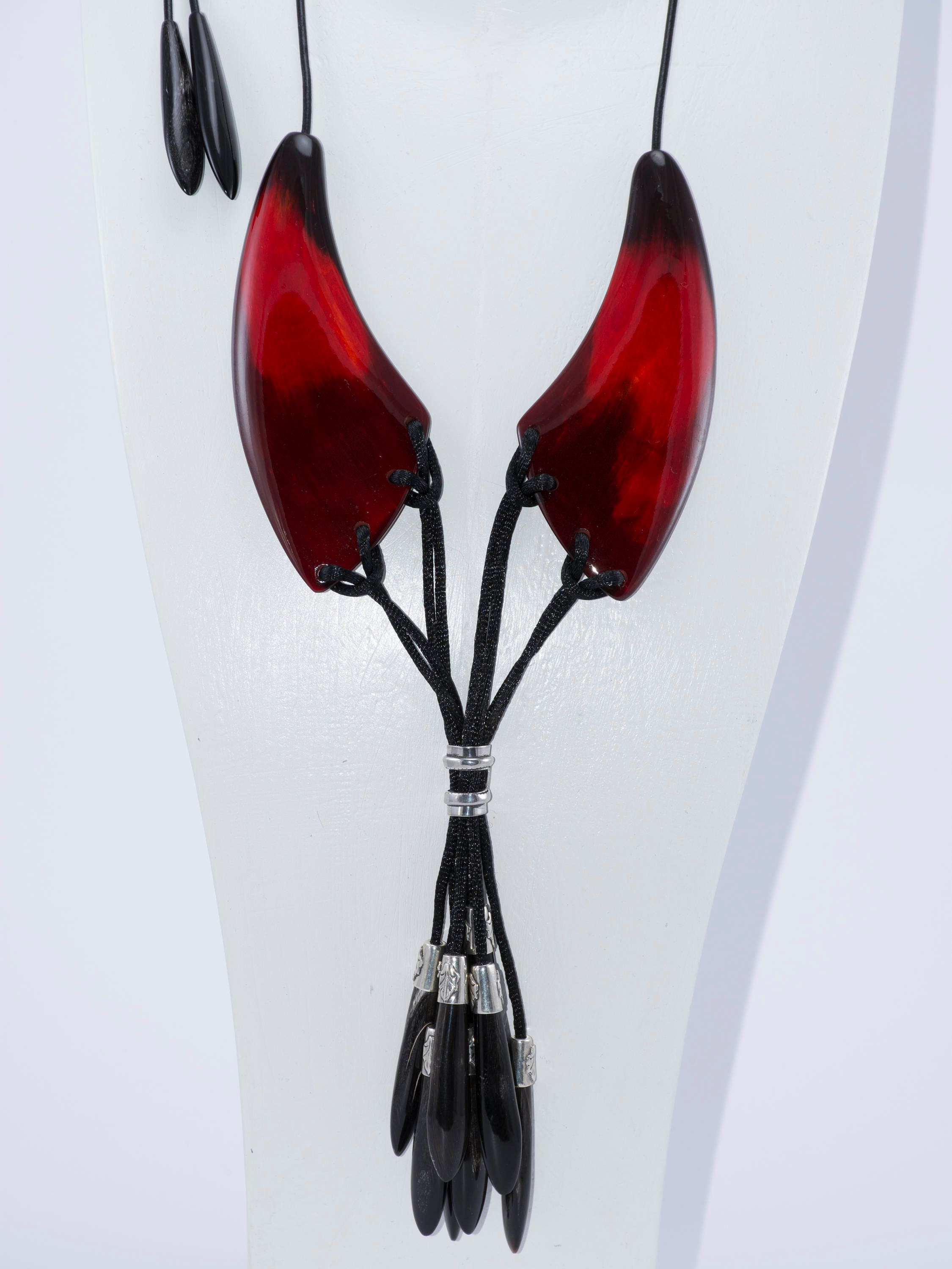 A beautiful dark red necklace made from natural horn with silver caps and teardrop-shaped endings, showcasing its unique craftsmanship.