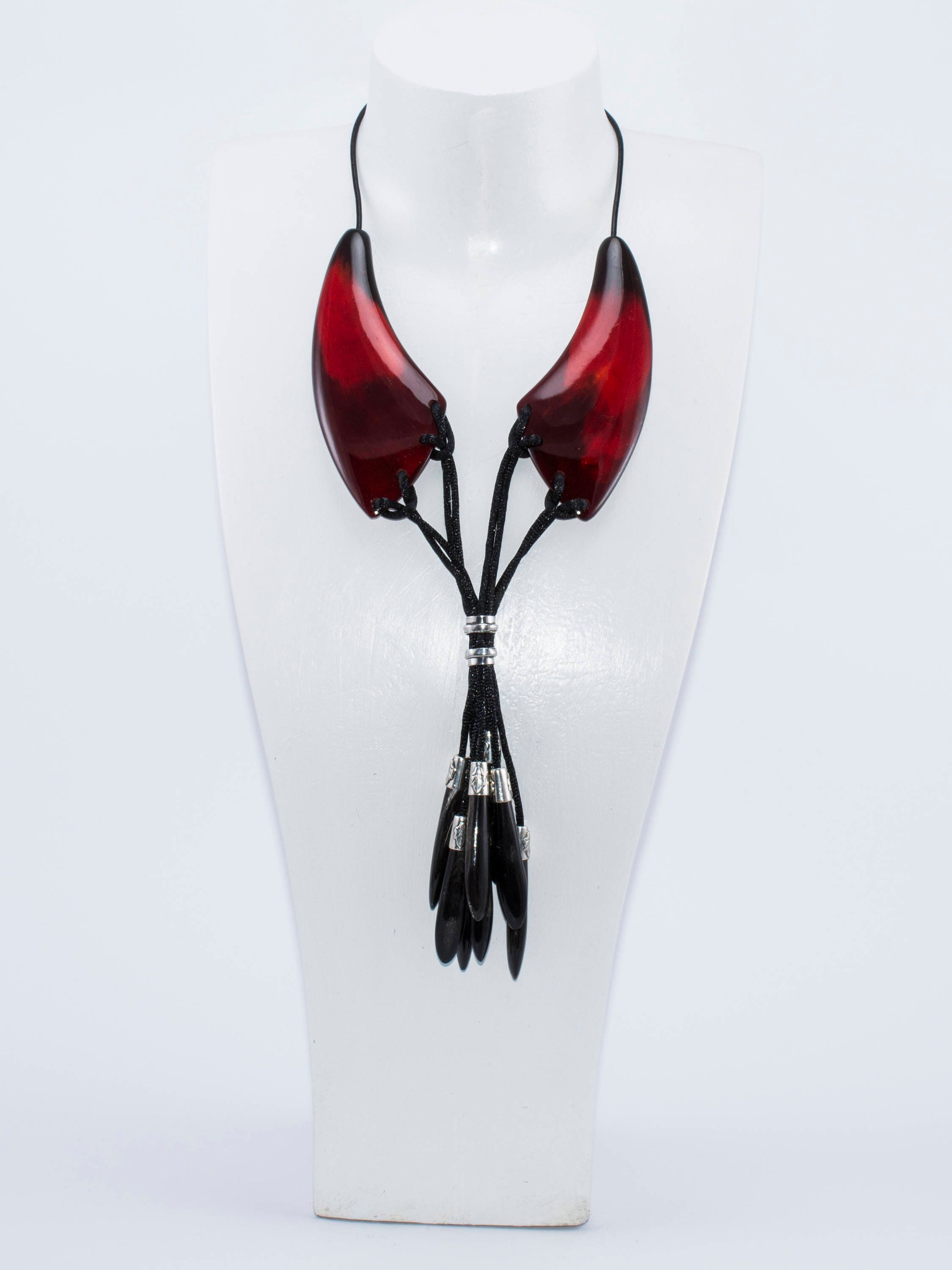 A beautiful dark red necklace made from natural horn with silver caps and teardrop-shaped endings, showcasing its unique craftsmanship.