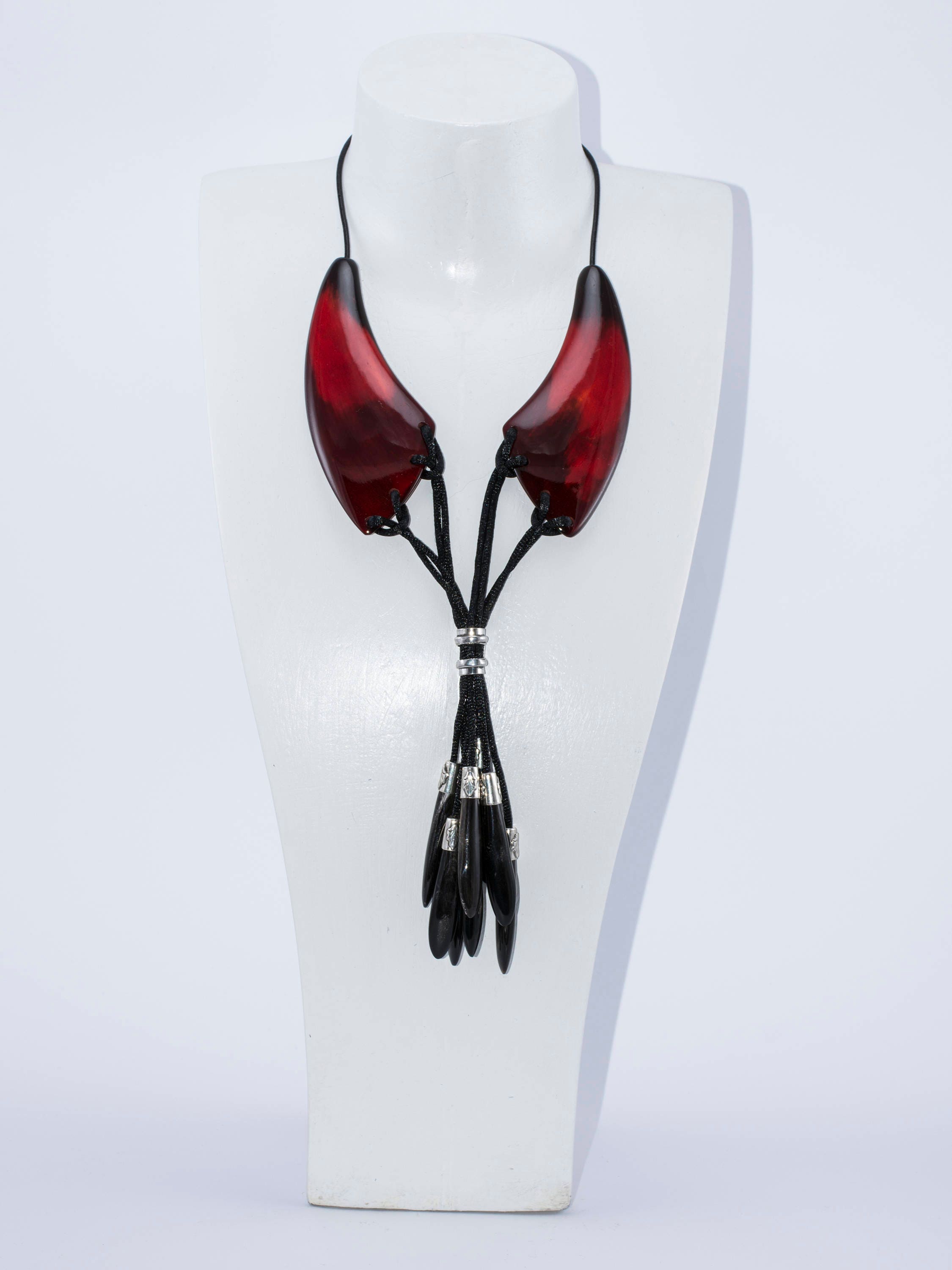A beautiful dark red necklace made from natural horn with silver caps and teardrop-shaped endings, showcasing its unique craftsmanship.