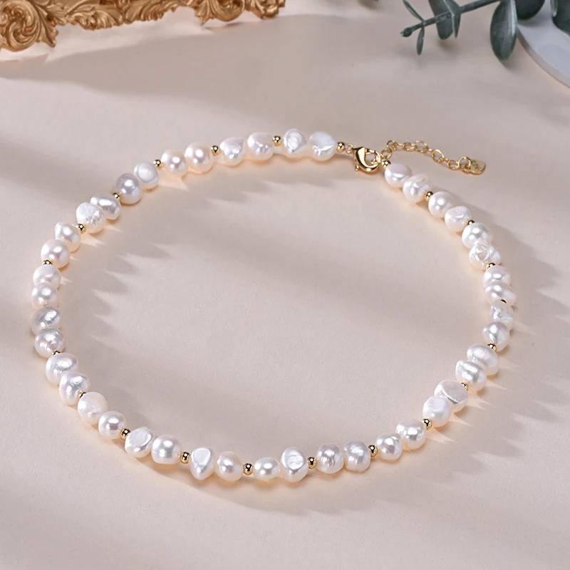 A luxurious designer necklace featuring genuine white freshwater pearls and elegant gold accents, showcasing its adjustable chain and unique pearl sizes.