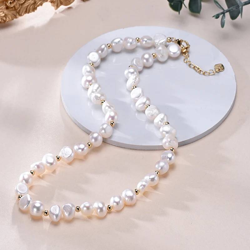 A luxurious designer necklace featuring genuine white freshwater pearls and elegant gold accents, showcasing its adjustable chain and unique pearl sizes.