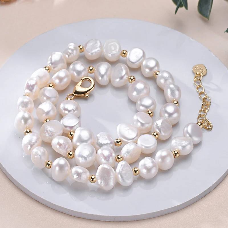A luxurious designer necklace featuring genuine white freshwater pearls and elegant gold accents, showcasing its adjustable chain and unique pearl sizes.