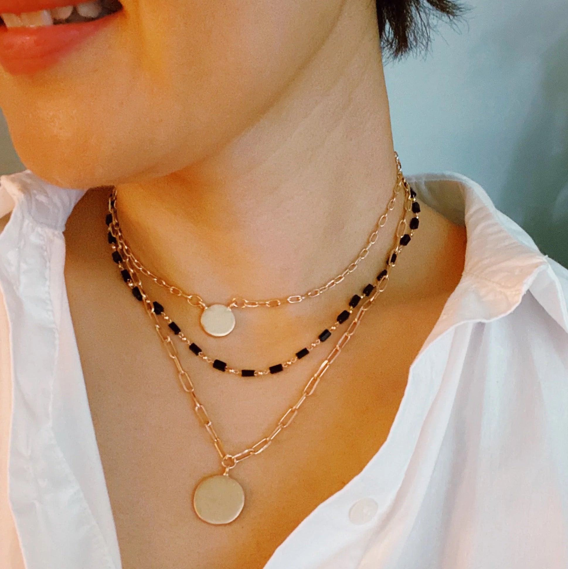 A stylish set of three necklaces featuring disc pendants and beaded designs, perfect for layering and versatile fashion.