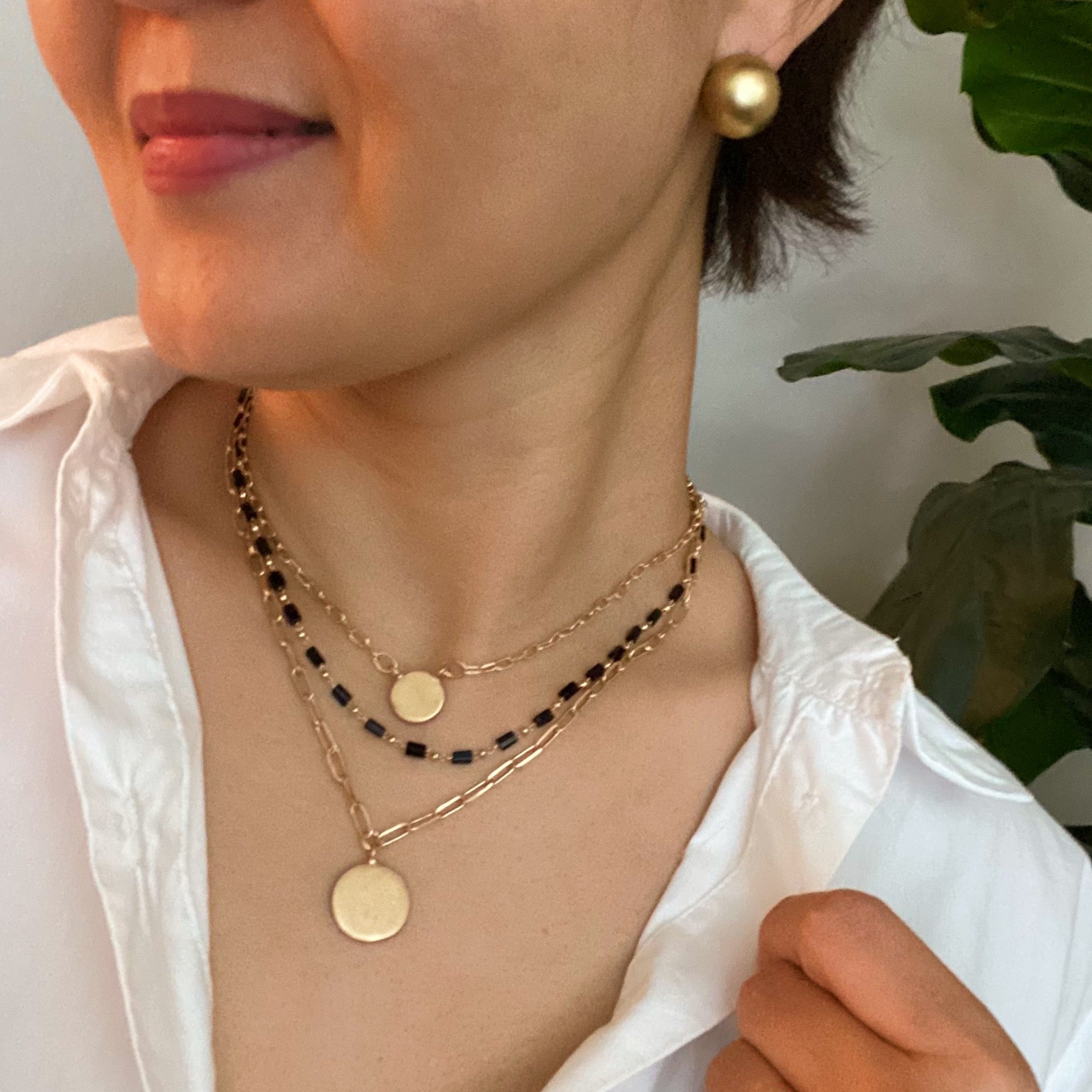 A stylish set of three necklaces featuring disc pendants and beaded designs, perfect for layering and versatile fashion.